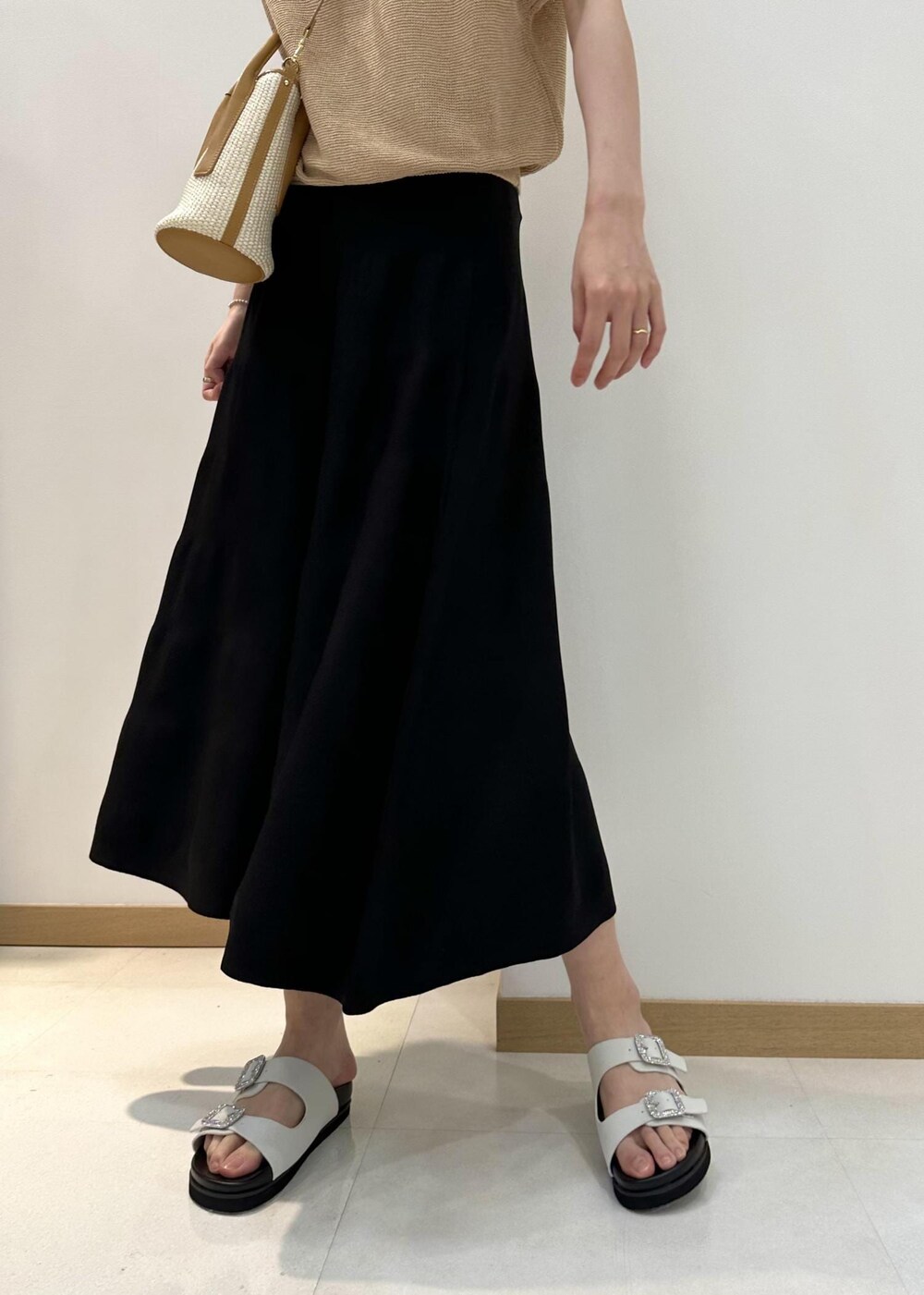 ベージュ系のハンドバッグ、ホワイト系のサンダル、ブラック系のスカートを着用したレディースの夏コーディネートの7枚目の写真