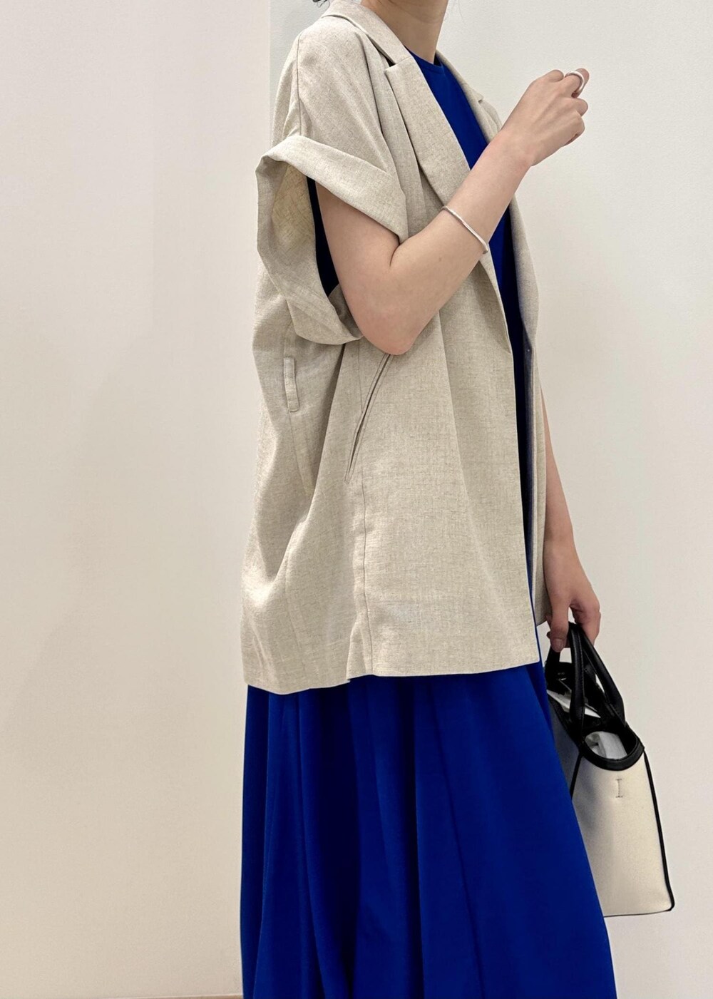 ブラック系のトートバッグ、ブルー系のサンダル、ブルー系のワンピースを着用したレディースの春コーディネートの6枚目の写真