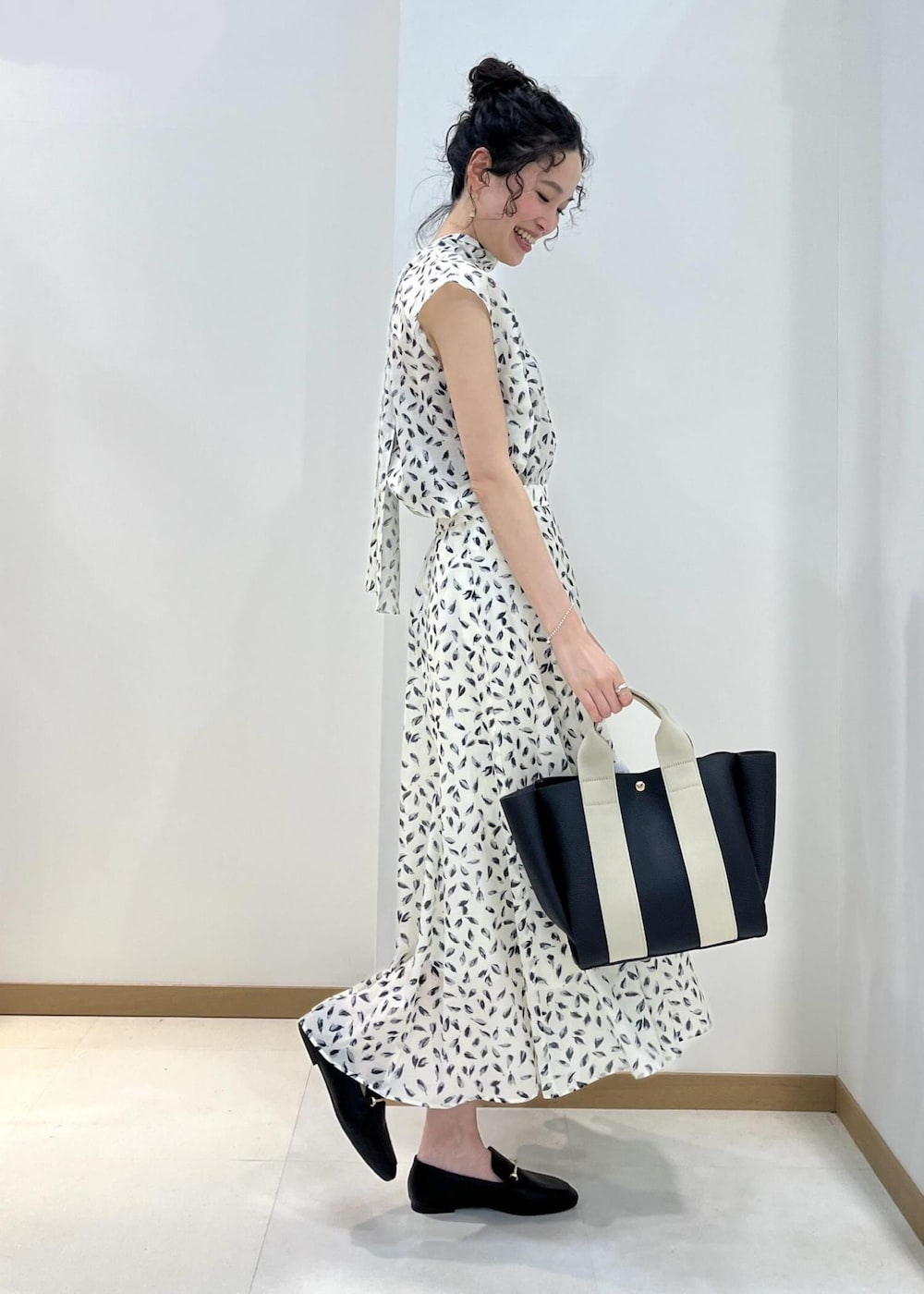 ブラック系のトートバッグ、ブラック系のレインシューズ、ホワイト系のシャツ/ブラウスを着用したレディースの春コーディネートの2枚目の写真