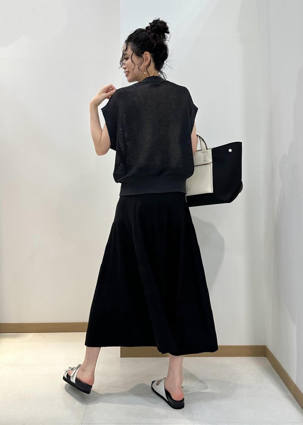 ブラック系のハンドバッグ、ホワイト系のサンダル、ブラック系のスカートを着用したレディースの夏コーディネートの3枚目の写真