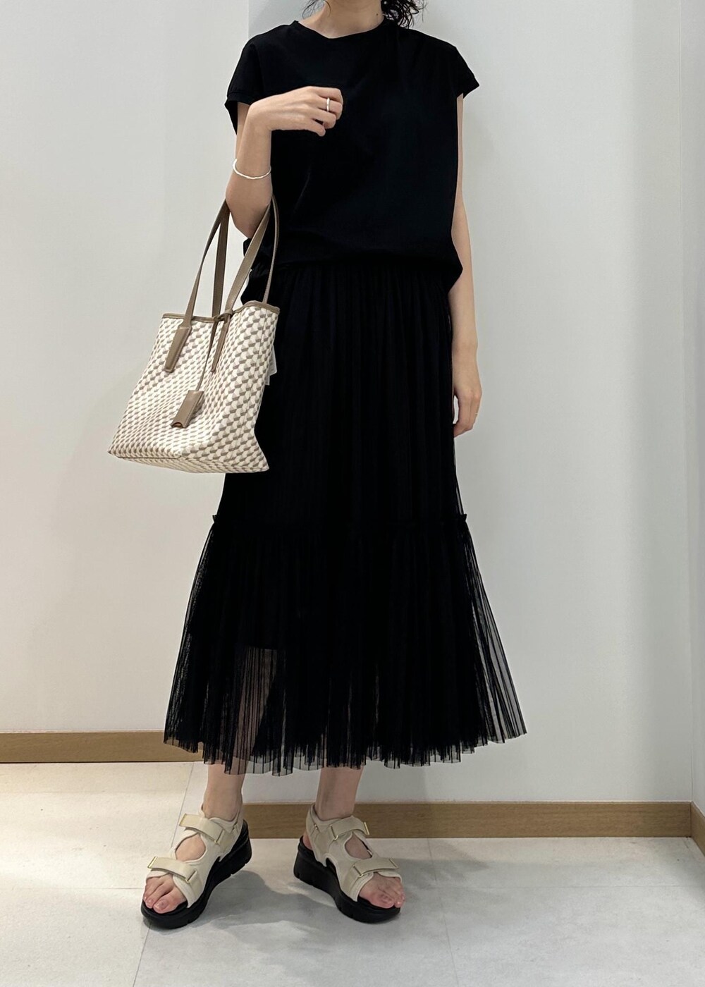 ベージュ系のトートバッグ、ホワイト系のサンダル、ブラック系のTシャツ/カットソーを着用したレディースの夏コーディネートの4枚目の写真