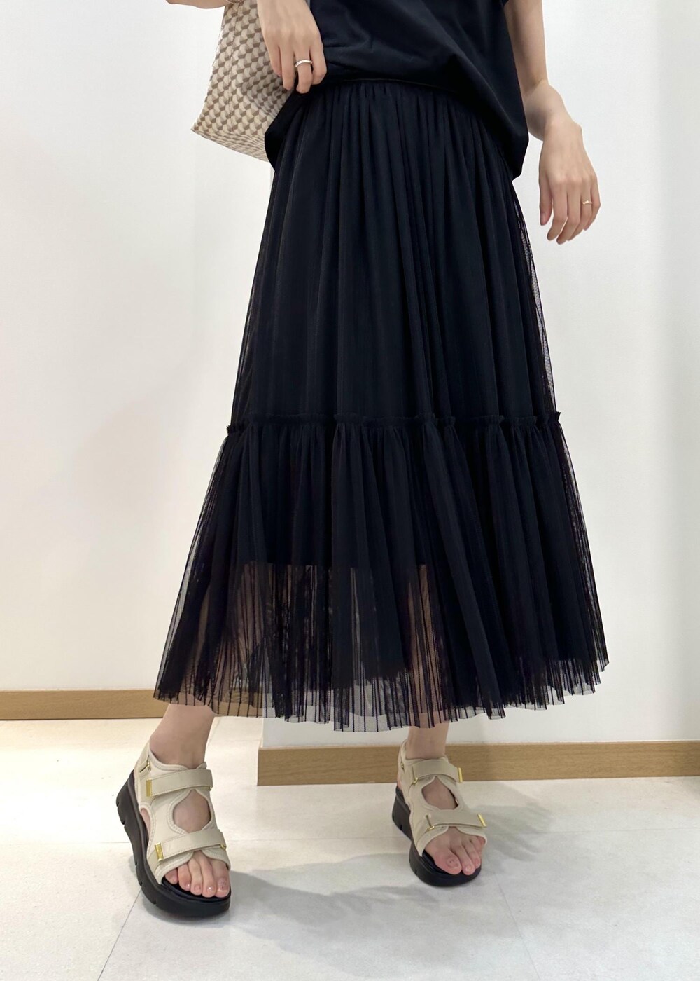 ベージュ系のトートバッグ、ホワイト系のサンダル、ブラック系のTシャツ/カットソーを着用したレディースの夏コーディネートの7枚目の写真