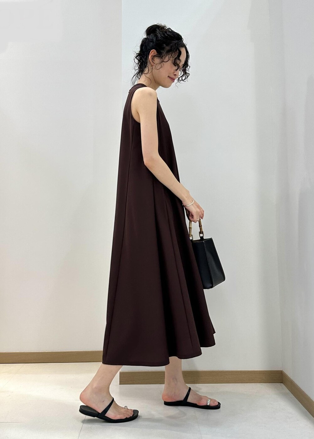 ブラック系のハンドバッグ、ブラック系のサンダル、ブラウン系のワンピースを着用したレディースの夏コーディネートの2枚目の写真