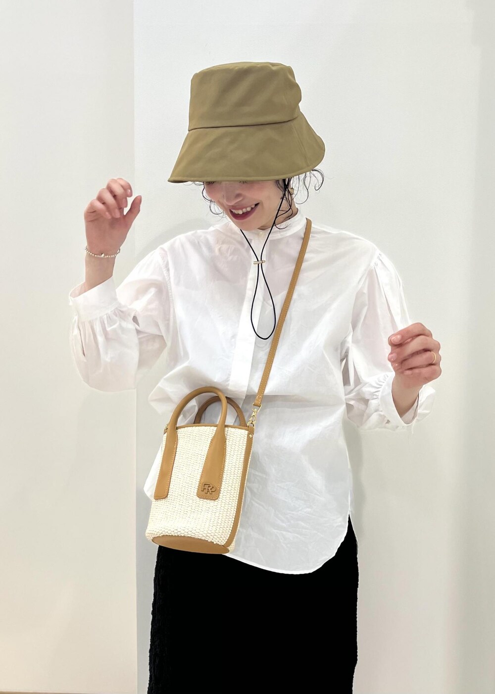 ホワイト系のシャツ/ブラウス、ブラック系のスカート、ベージュ系のハンドバッグを着用したレディースの春コーディネートの6枚目の写真