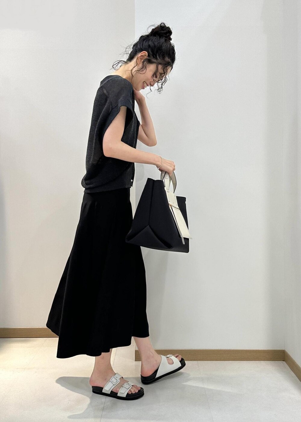 ブラック系のハンドバッグ、ホワイト系のサンダル、ブラック系のスカートを着用したレディースの夏コーディネートの2枚目の写真