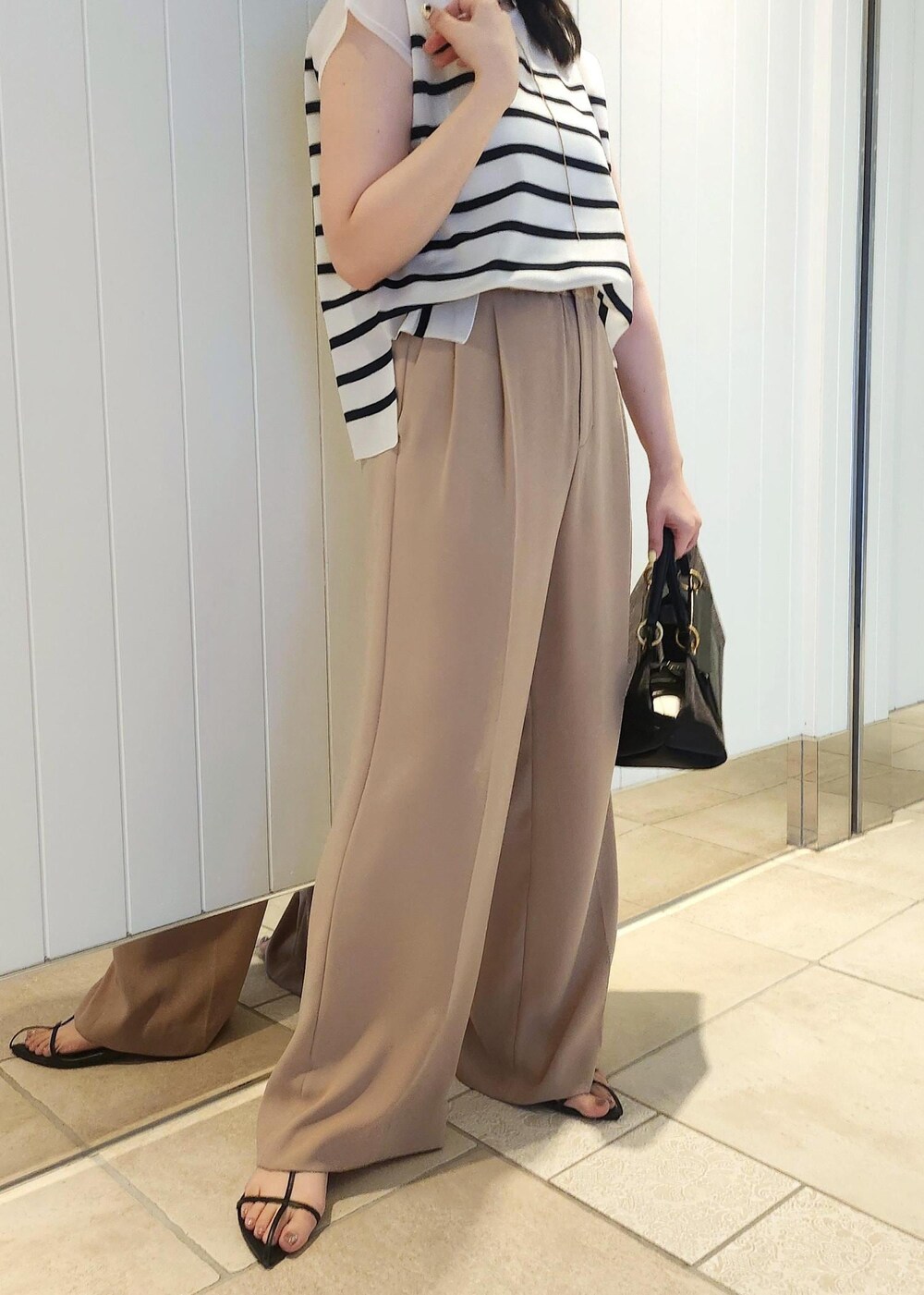 ブラック系のハンドバッグ、ベージュ系のその他パンツ、ブルー系のシャツ/ブラウスを着用したレディースの夏コーディネートの7枚目の写真