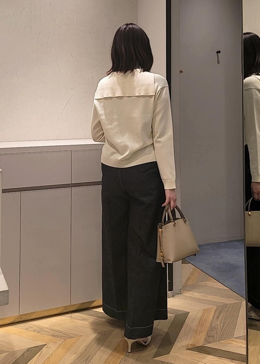 ベージュ系のハンドバッグ、ブルー系のデニムパンツ、ホワイト系のサンダルを着用したレディースの春コーディネートの2枚目の写真