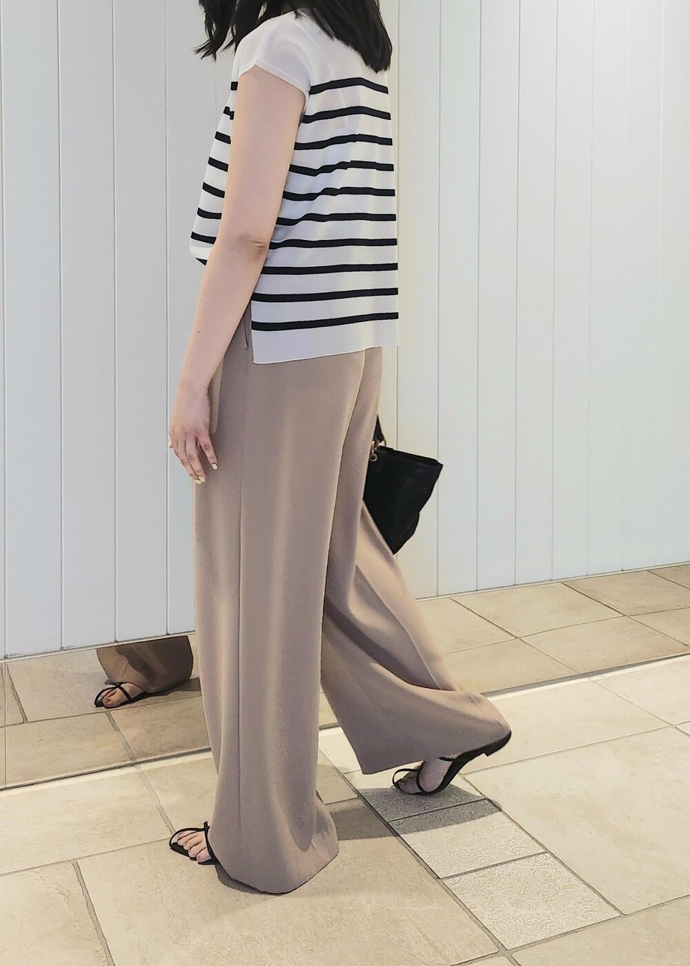 ブラック系のハンドバッグ、ベージュ系のその他パンツ、ブルー系のシャツ/ブラウスを着用したレディースの夏コーディネートの3枚目の写真