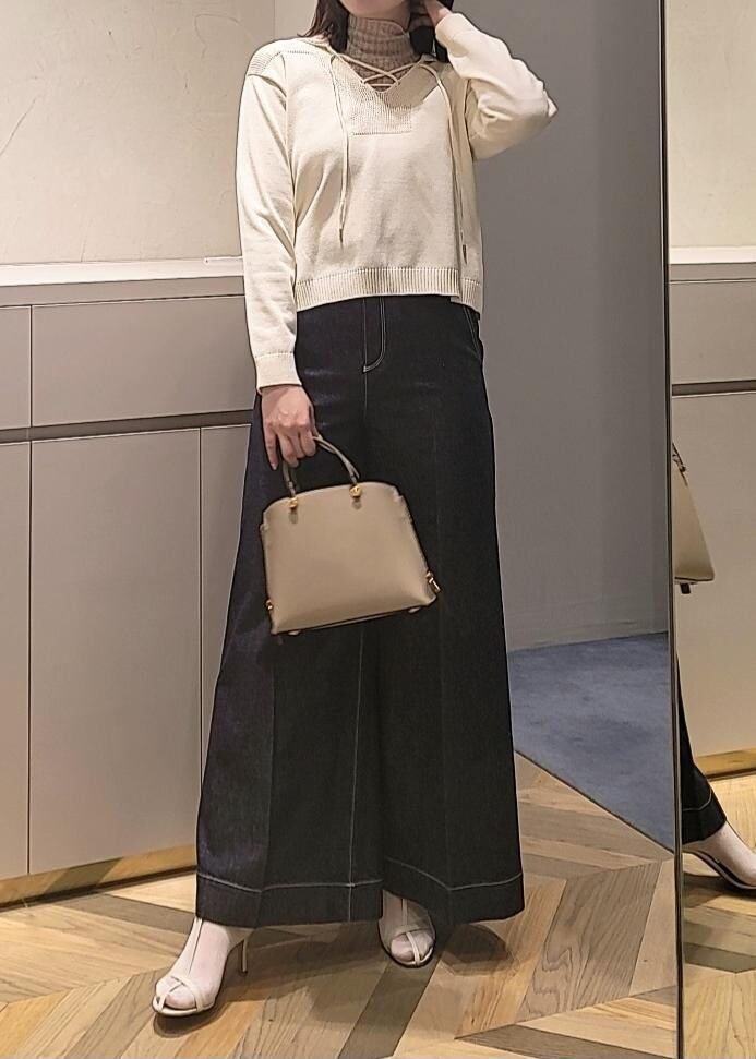 ベージュ系のハンドバッグ、ブルー系のデニムパンツ、ホワイト系のサンダルを着用したレディースの春コーディネートの3枚目の写真