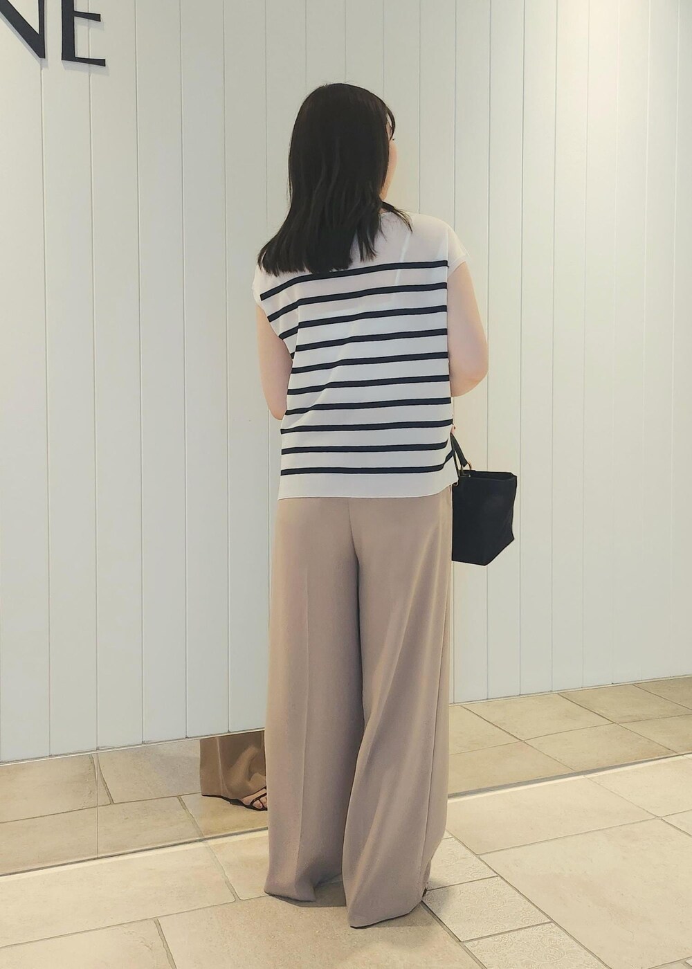 ブラック系のハンドバッグ、ベージュ系のその他パンツ、ブルー系のシャツ/ブラウスを着用したレディースの夏コーディネートの2枚目の写真