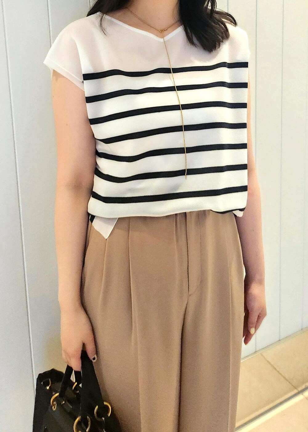 ブラック系のハンドバッグ、ベージュ系のその他パンツ、ブルー系のシャツ/ブラウスを着用したレディースの夏コーディネートの4枚目の写真