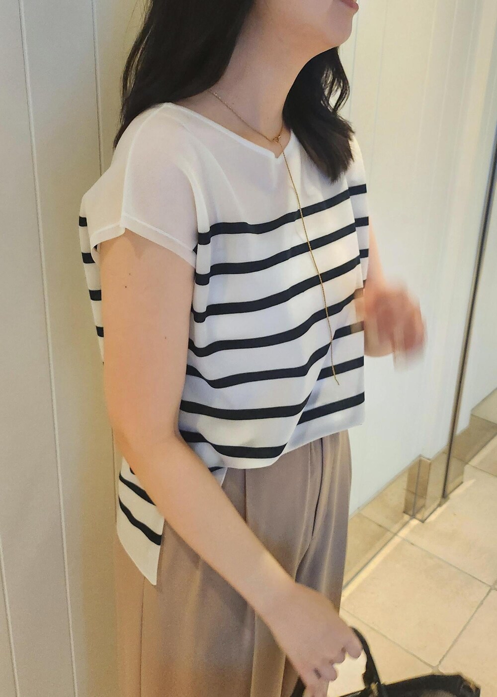 ブラック系のハンドバッグ、ベージュ系のその他パンツ、ブルー系のシャツ/ブラウスを着用したレディースの夏コーディネートの5枚目の写真