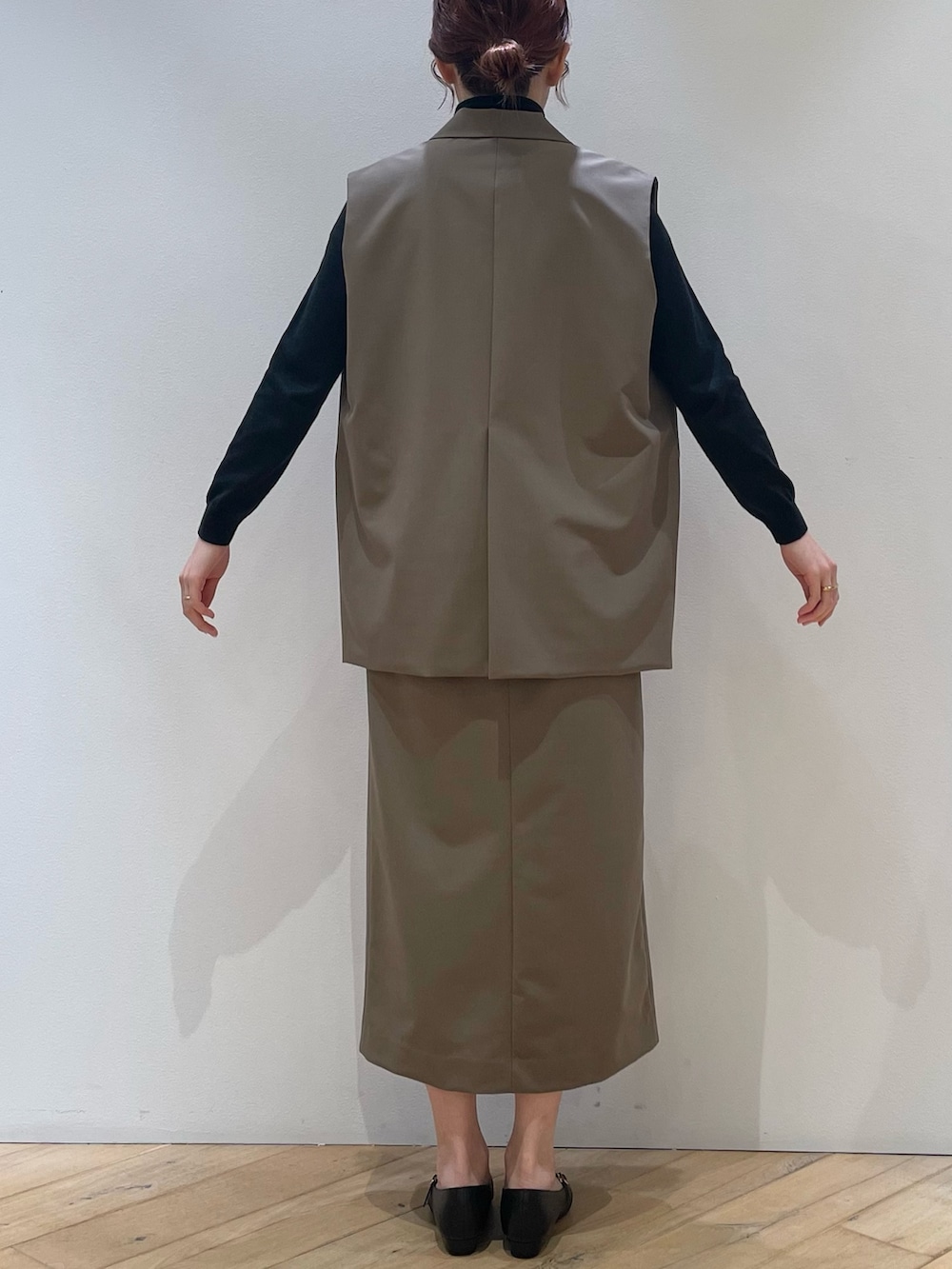 ブラウン系のベスト、ブラック系のパンプス、ブラウン系のスカートを着用したレディースの冬コーディネートの4枚目の写真