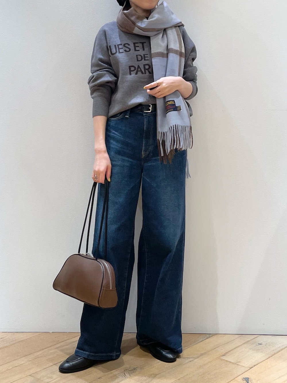 ブラウン系のボストンバッグ、ブラック系のローファー、ブルー系のデニムパンツを着用したレディースの秋コーディネートの7枚目の写真