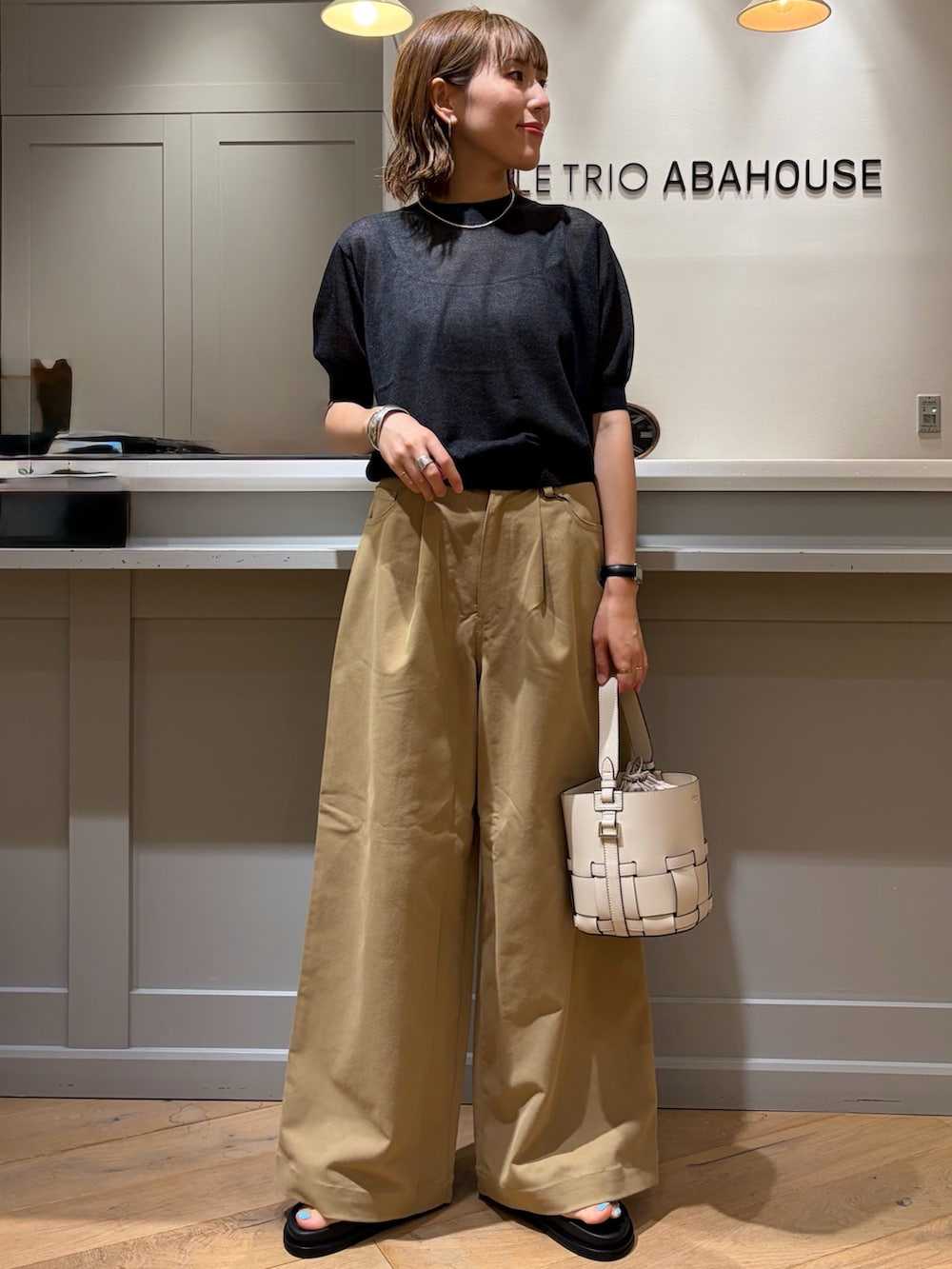 ブラック系のニット/セーター、ベージュ系のその他パンツ、ブラック系のボストンバッグを着用したレディースの夏コーディネートの6枚目の写真