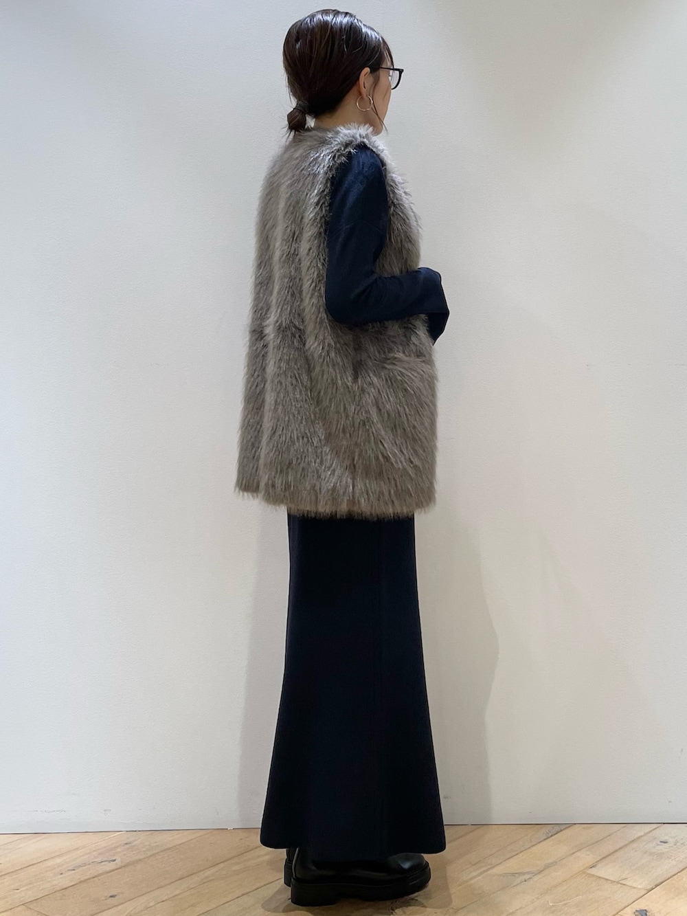 ブラウン系のベスト、ブルー系のニット/セーター、ブルー系のスカートを着用したレディースの秋コーディネートの2枚目の写真