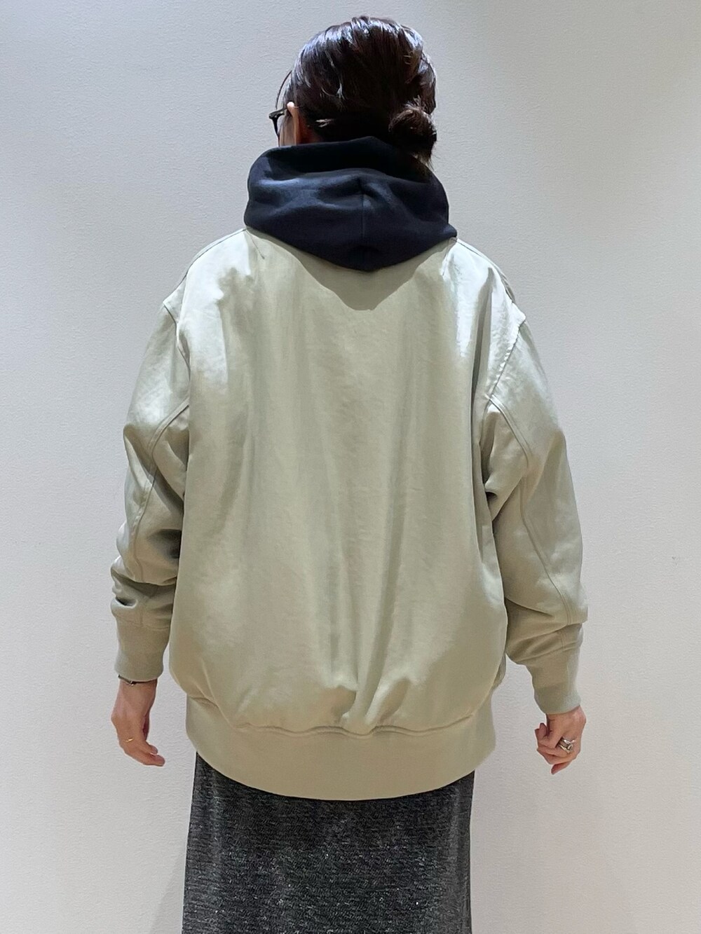 グリーン系のブルゾン、ブルー系のパーカー、シルバー系のスカートを着用したレディースの秋コーディネートの5枚目の写真