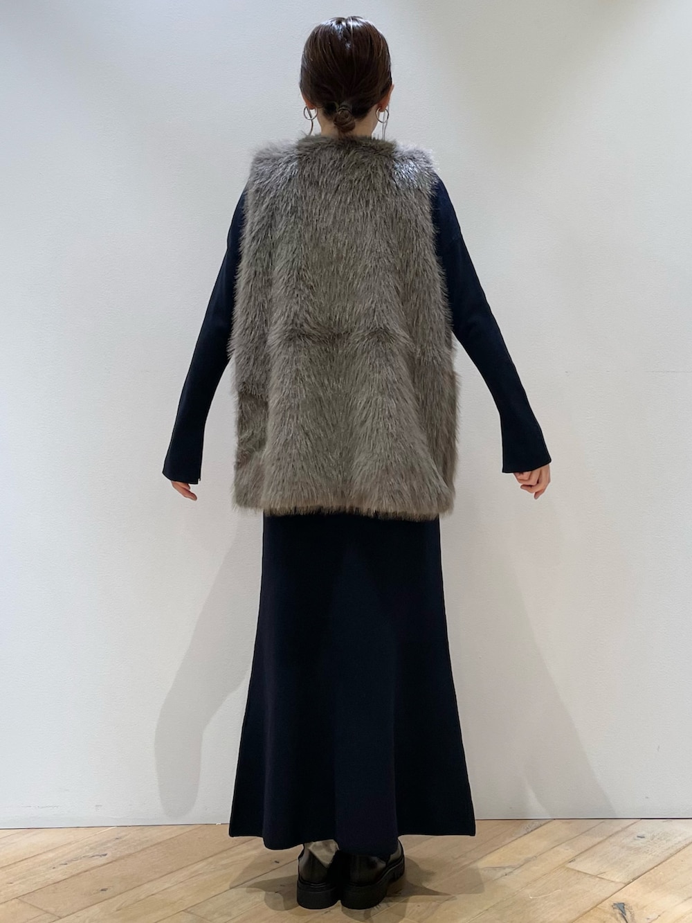 ブラウン系のベスト、ブルー系のニット/セーター、ブルー系のスカートを着用したレディースの秋コーディネートの5枚目の写真