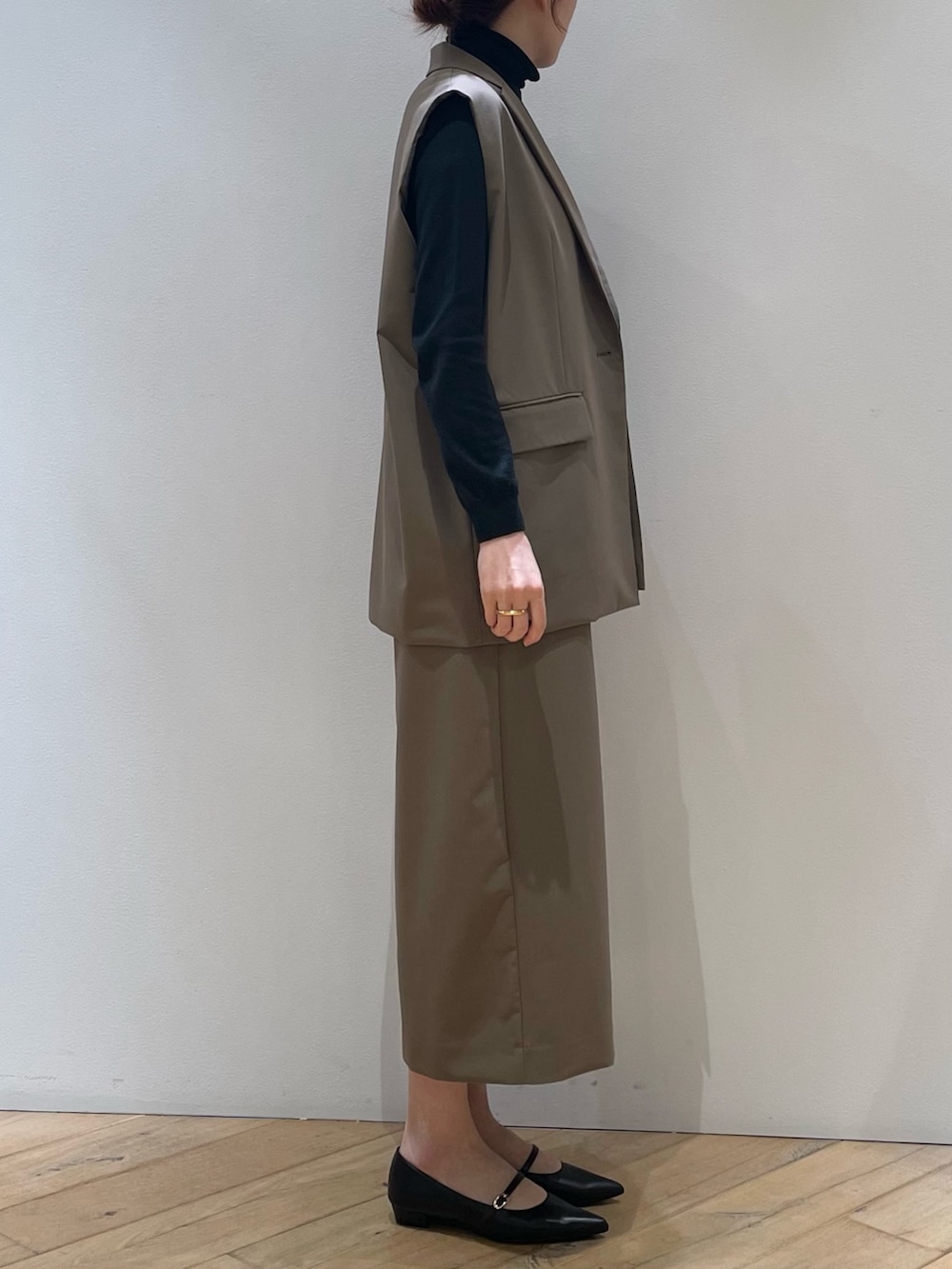 ブラウン系のベスト、ブラック系のパンプス、ブラウン系のスカートを着用したレディースの冬コーディネートの3枚目の写真