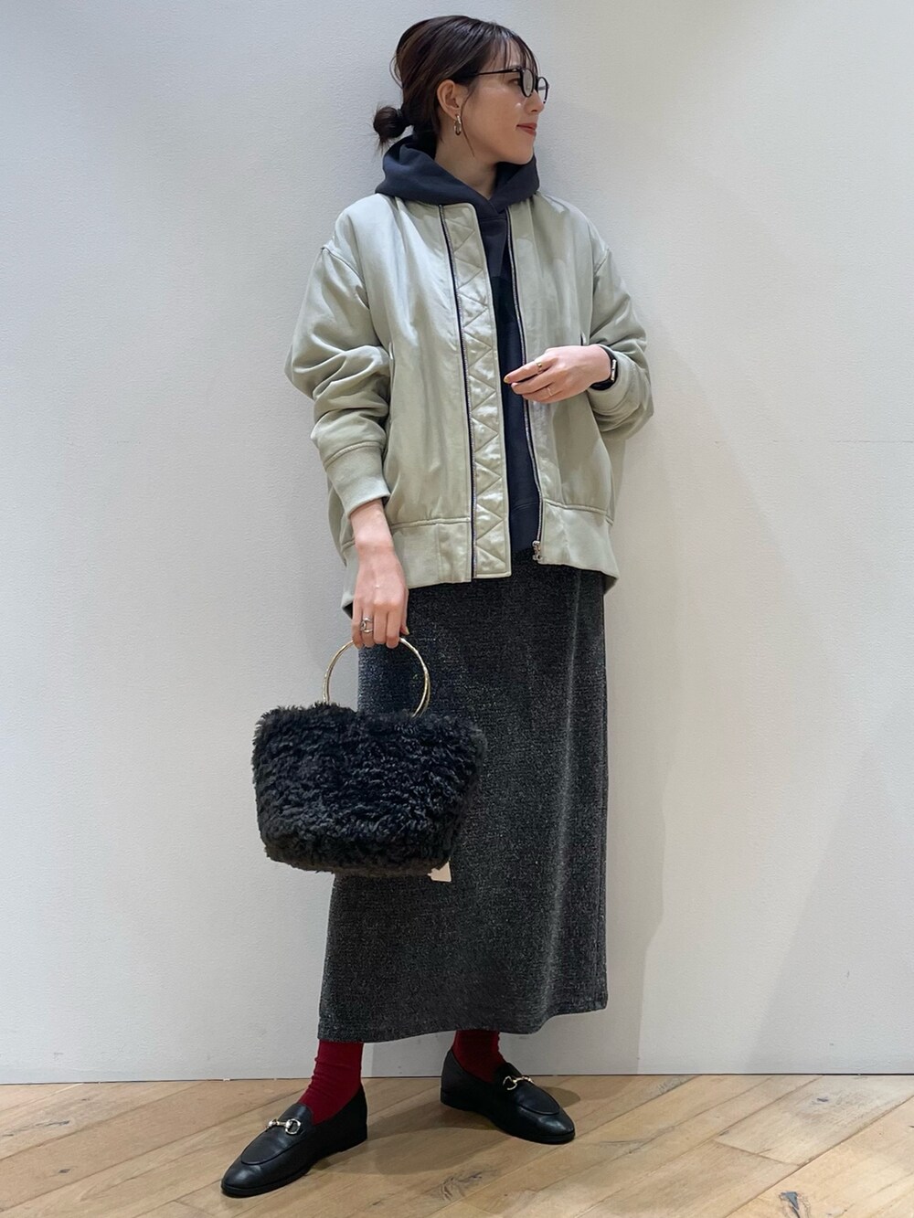 グリーン系のブルゾン、ブルー系のパーカー、シルバー系のスカートを着用したレディースの秋コーディネートの2枚目の写真