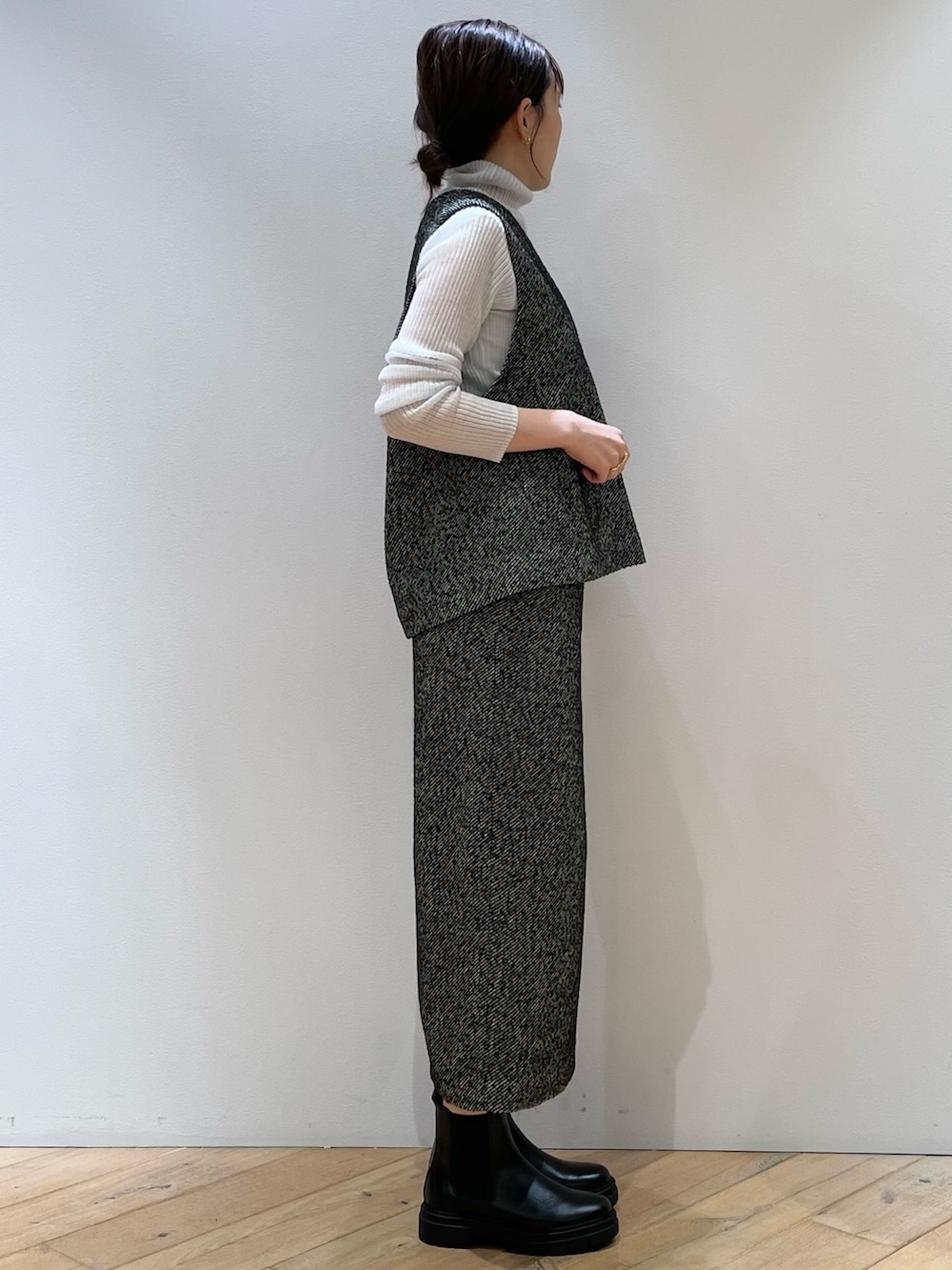 ブラック系のスカート、ブラック系のベスト、グレー系のニット/セーターを着用したレディースの秋コーディネートの3枚目の写真