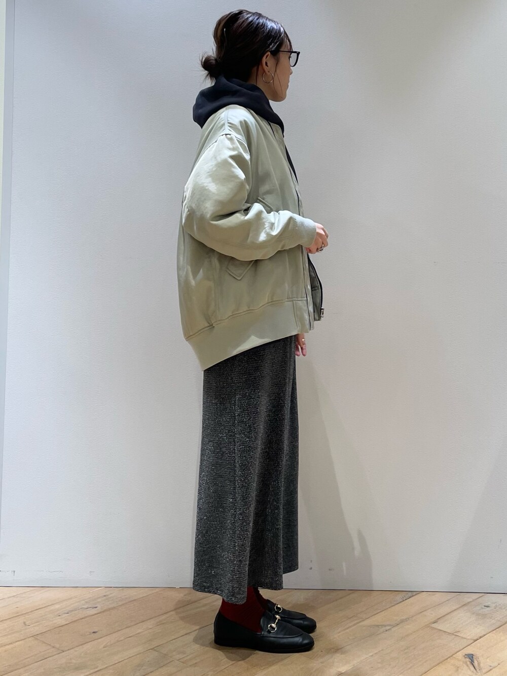 グリーン系のブルゾン、ブルー系のパーカー、シルバー系のスカートを着用したレディースの秋コーディネートの3枚目の写真