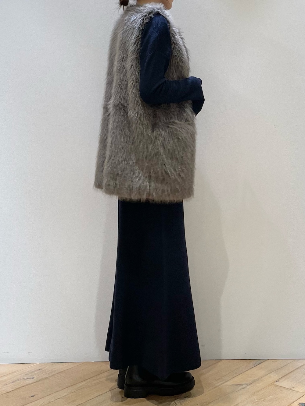 ブラウン系のベスト、ブルー系のニット/セーター、ブルー系のスカートを着用したレディースの秋コーディネートの3枚目の写真