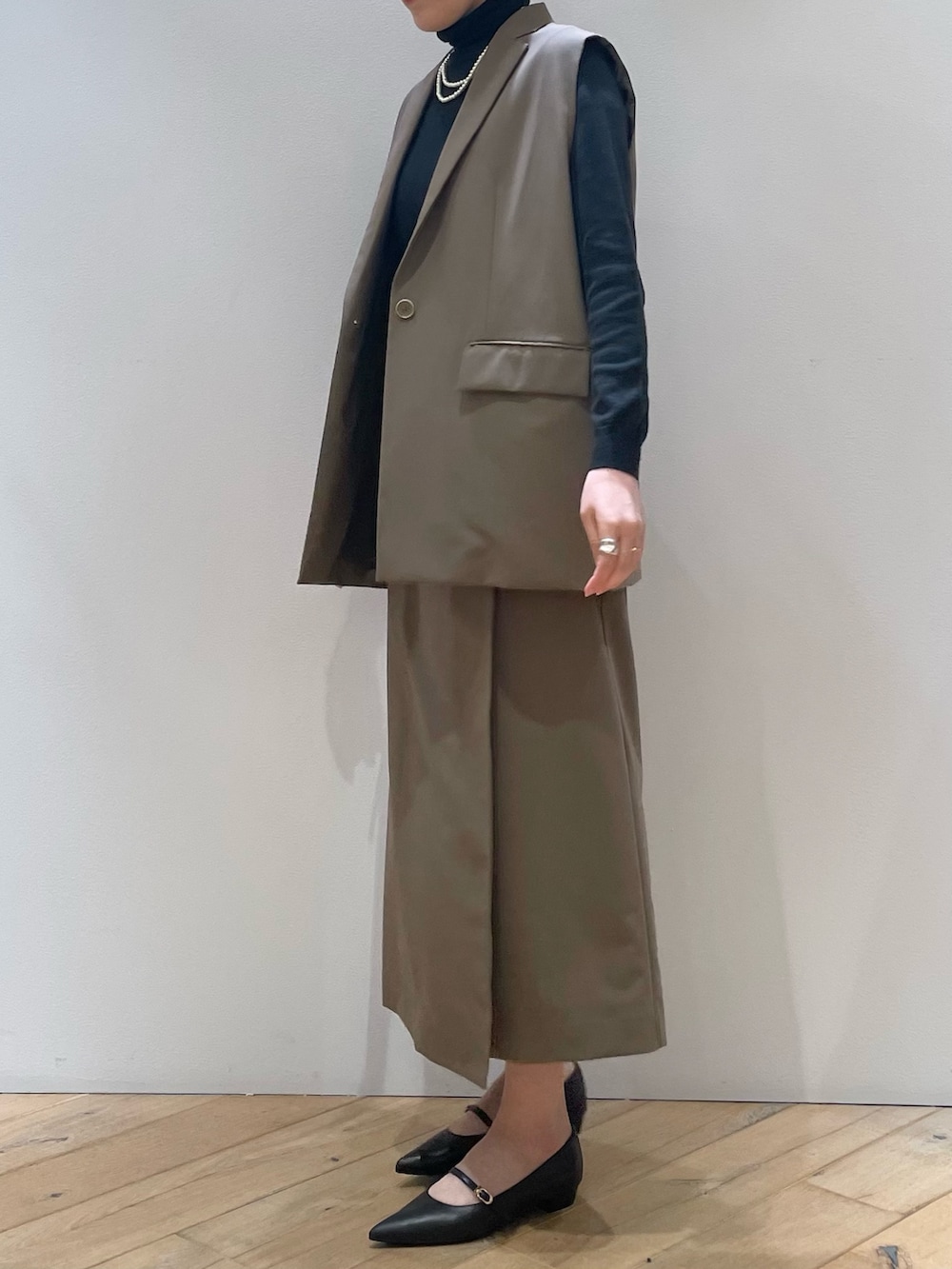 ブラウン系のベスト、ブラック系のパンプス、ブラウン系のスカートを着用したレディースの冬コーディネートの5枚目の写真