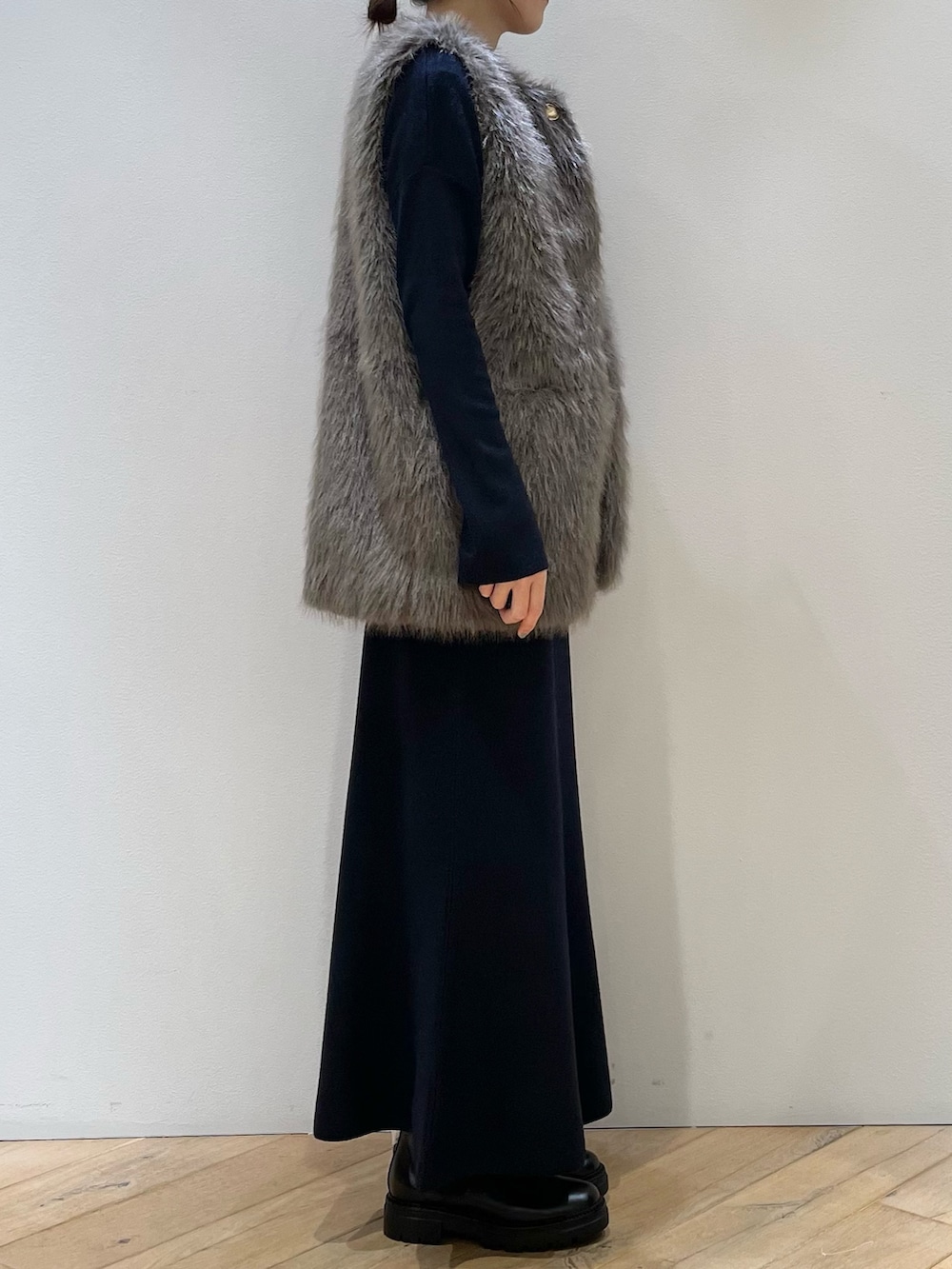 ブラウン系のベスト、ブルー系のニット/セーター、ブルー系のスカートを着用したレディースの秋コーディネートの4枚目の写真