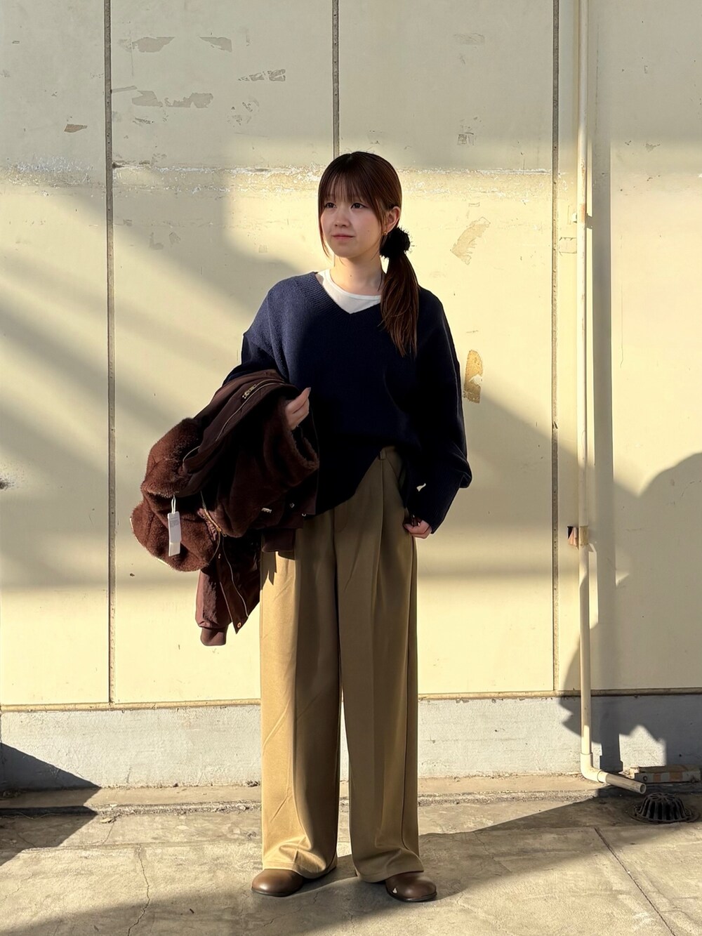 ブラウン系のブルゾン、ブルー系のニット/セーター、ベージュ系のその他パンツを着用したレディースの冬コーディネートの2枚目の写真