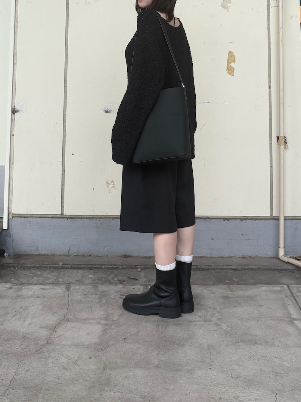 ブラック系のニット/セーター、ブラック系のその他パンツ、ブラック系のブーツを着用したレディースの秋コーディネートの2枚目の写真