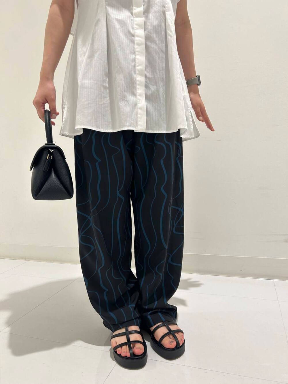 ブルー系のその他パンツ、ブラック系のサンダル、ホワイト系のシャツ/ブラウスを着用したレディースの夏コーディネートの3枚目の写真