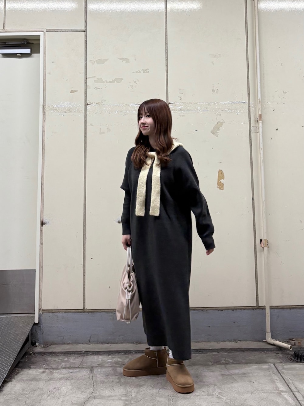 グレー系のワンピース、ベージュ系のブーツ、ホワイト系のショルダーバッグを着用したレディースの秋コーディネートの2枚目の写真