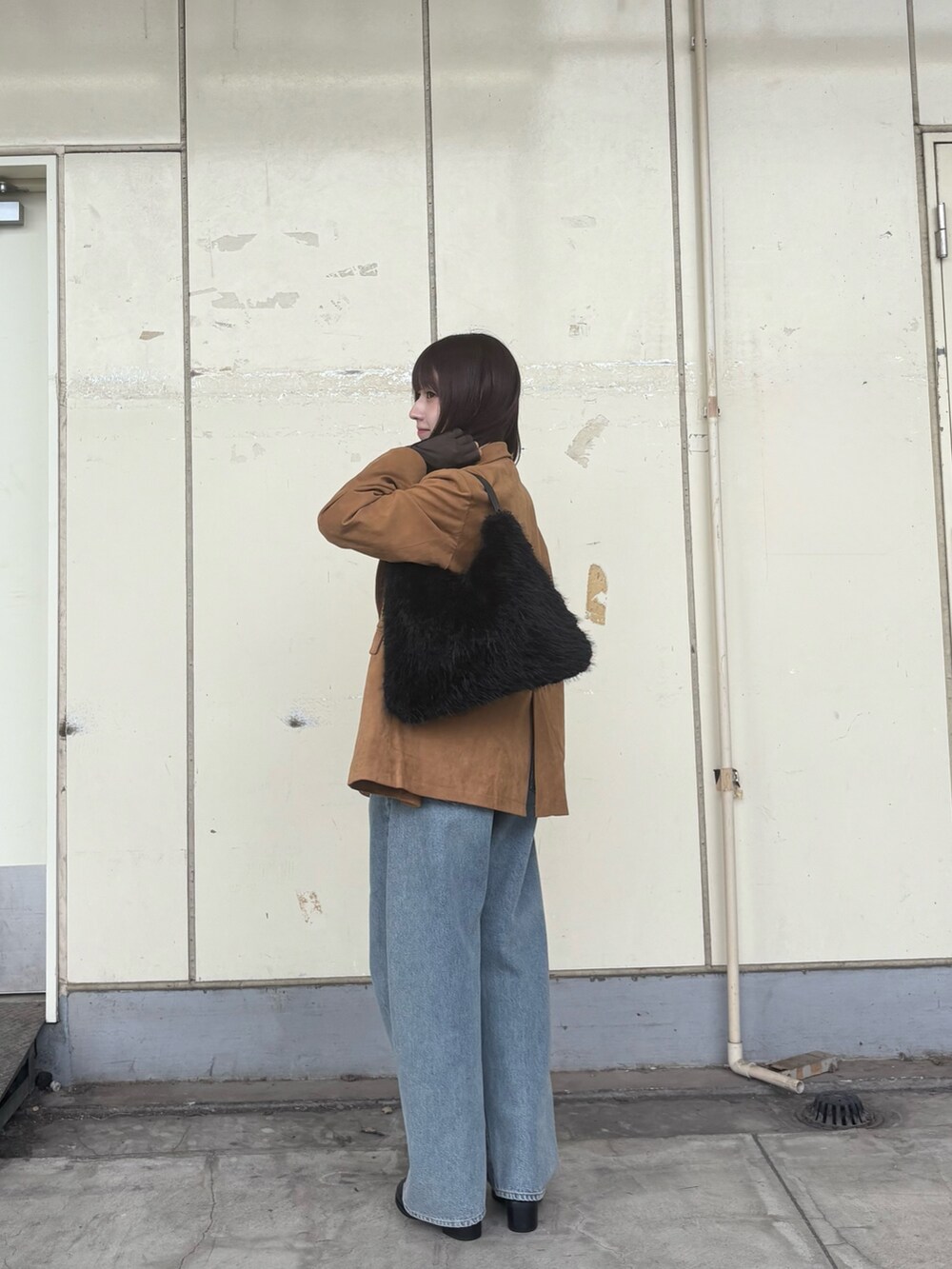 ブラック系のハンドバッグ、イエロー系のその他アウター、ブルー系のデニムパンツを着用したレディースの秋コーディネートの2枚目の写真