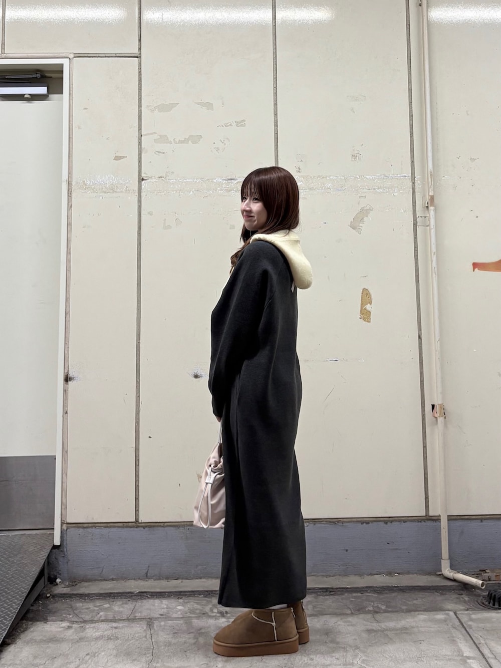 グレー系のワンピース、ベージュ系のブーツ、ホワイト系のショルダーバッグを着用したレディースの秋コーディネートの3枚目の写真