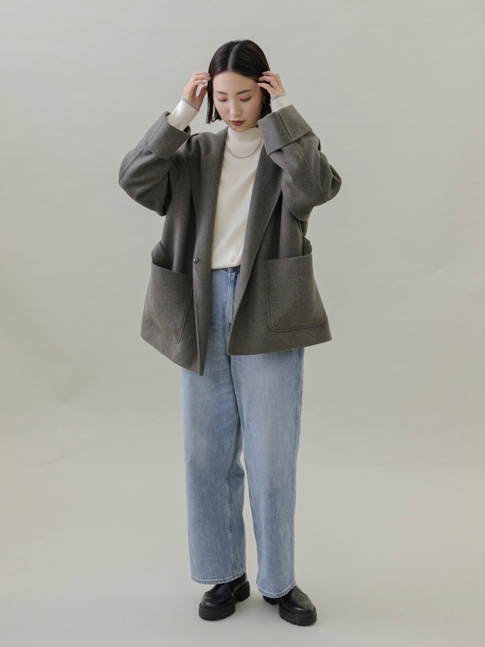 ブルー系のデニムパンツ、ブラック系のブーツ、グレー系のその他アウターを着用したレディースの秋コーディネートの2枚目の写真