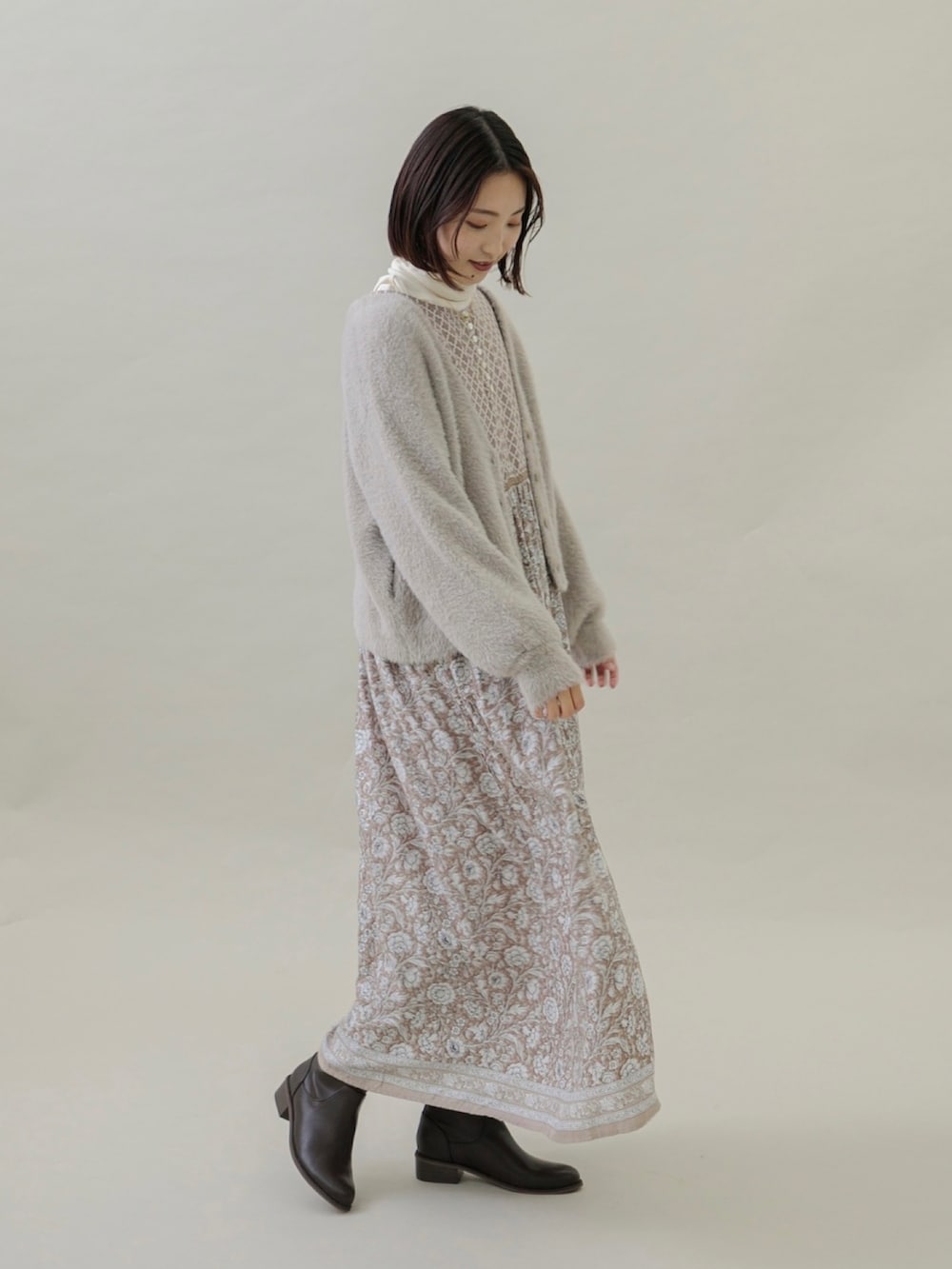 ベージュ系のワンピース、ベージュ系のカーディガン/ボレロ、ブラウン系のブーツを着用したレディースの秋コーディネートの2枚目の写真