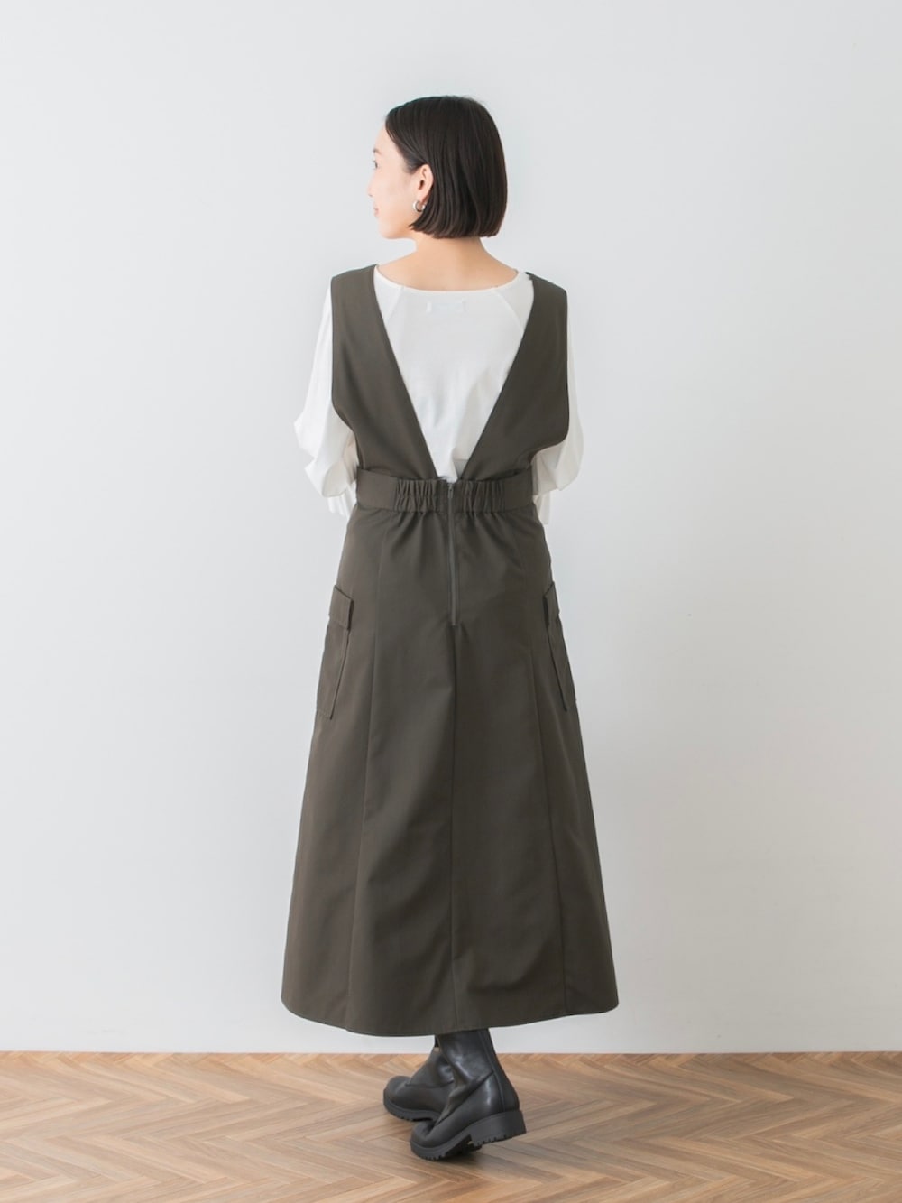 ブラック系のハンドバッグ、グリーン系のジャンパースカート、ホワイト系のTシャツ/カットソーを着用したレディースの夏コーディネートの3枚目の写真