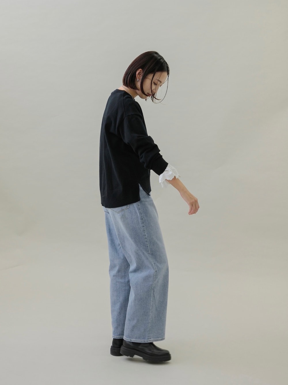 ブラック系のショルダーバッグ、ブルー系のデニムパンツ、ブラック系のブーツを着用したレディースの秋コーディネートの2枚目の写真