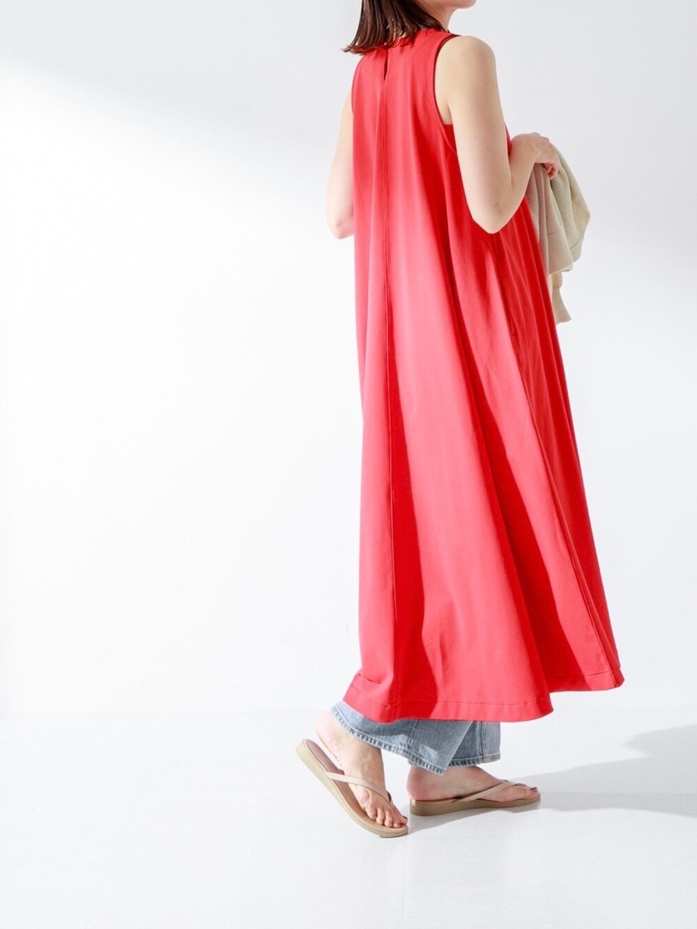 レッド系のワンピース、ブルー系のデニムパンツ、ゴールド系のネックレスを着用したレディースの夏コーディネートの2枚目の写真