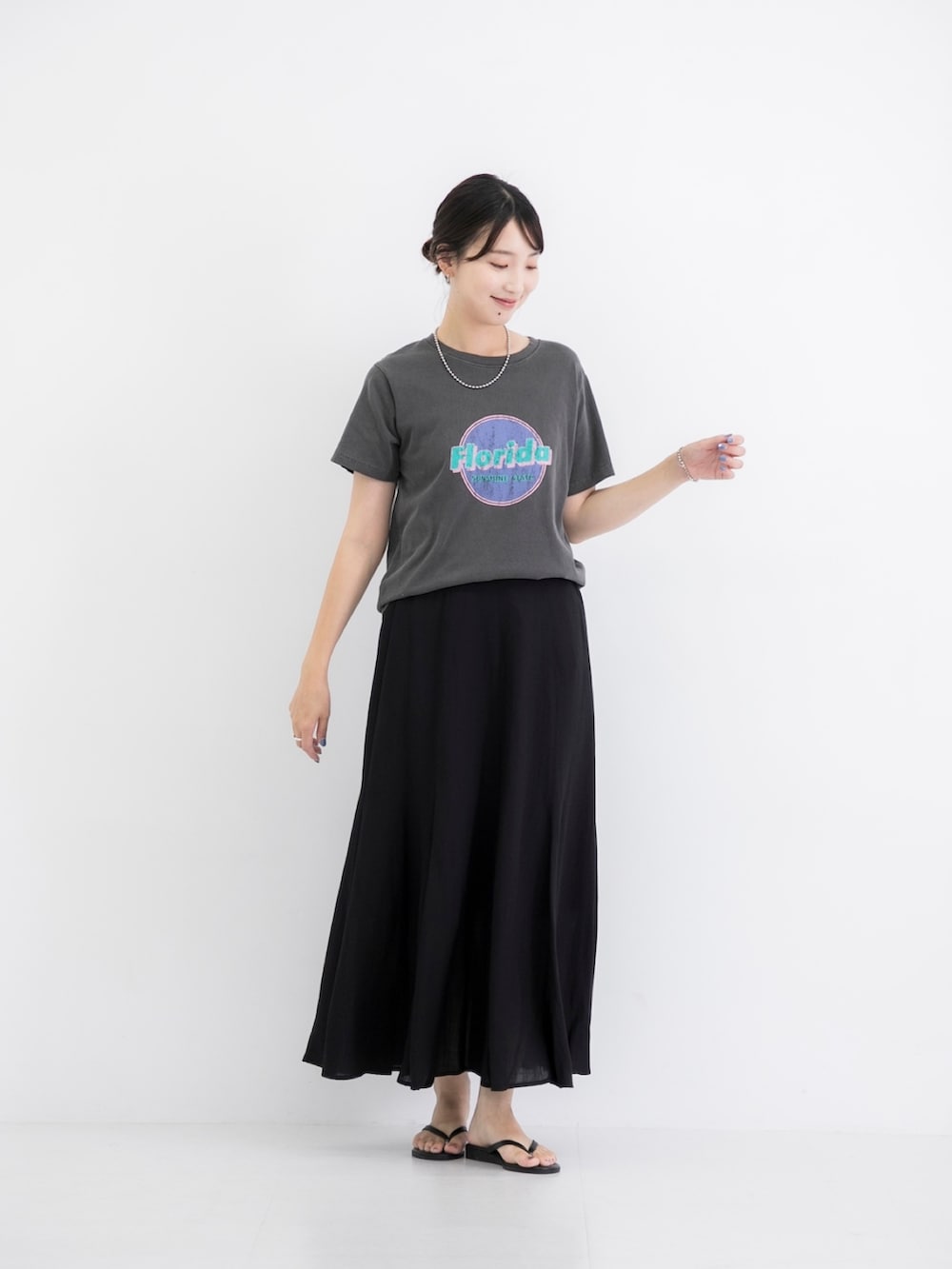 ブラック系のスカート、ブラック系のTシャツ/カットソー、シルバー系のネックレスを着用したレディースの夏コーディネートの2枚目の写真