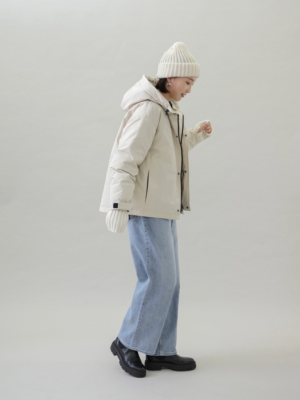 ベージュ系のダウンジャケット/コート、ブルー系のデニムパンツ、ブラック系のブーツを着用したレディースの秋コーディネートの2枚目の写真