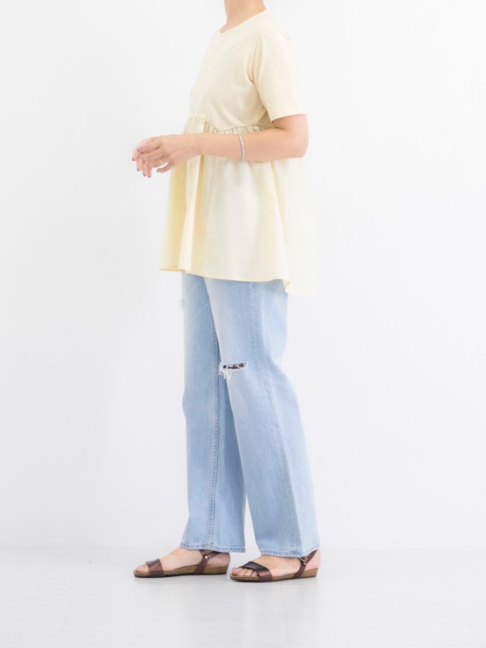 イエロー系のTシャツ/カットソー、ブルー系のデニムパンツ、ブラウン系のサンダルを着用したレディースの夏コーディネートの2枚目の写真