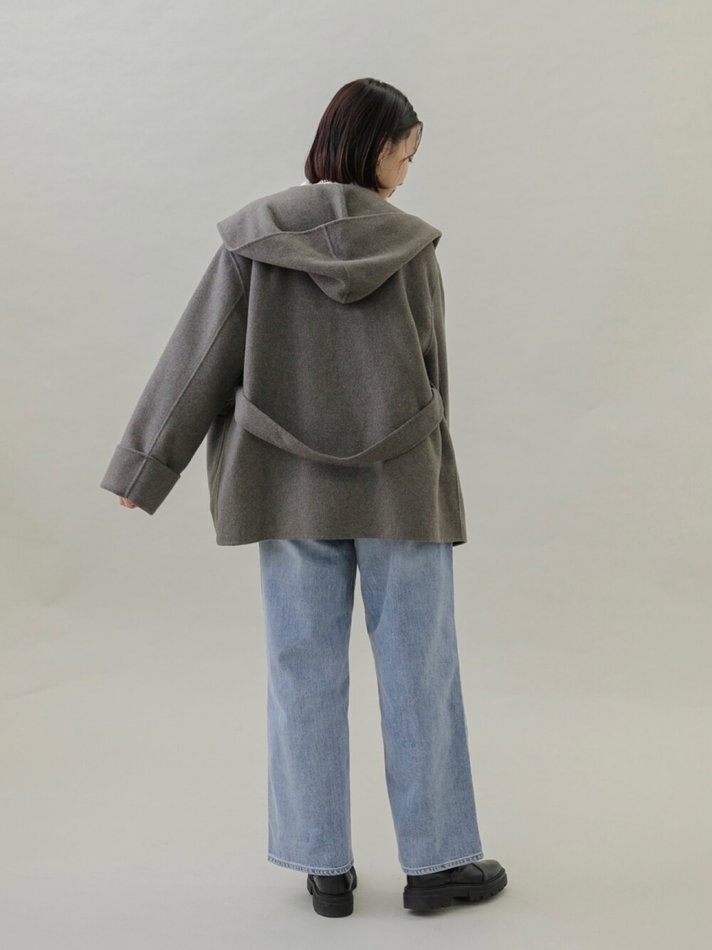 ブルー系のデニムパンツ、ブラック系のブーツ、グレー系のその他アウターを着用したレディースの秋コーディネートの4枚目の写真