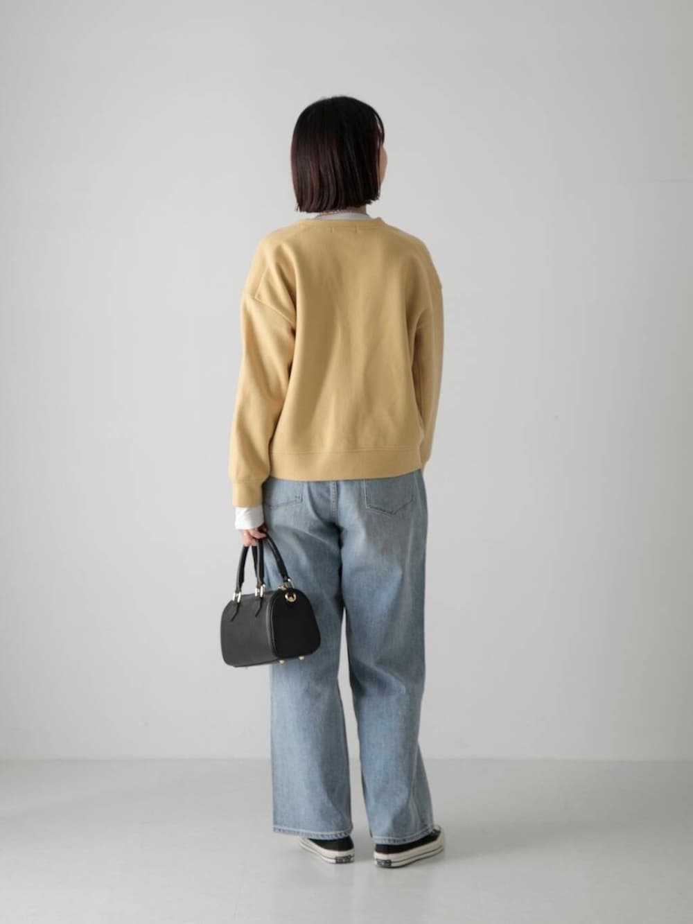 ブルー系のデニムパンツ、ホワイト系のTシャツ/カットソー、ブラック系のボストンバッグを着用したレディースの秋コーディネートの3枚目の写真