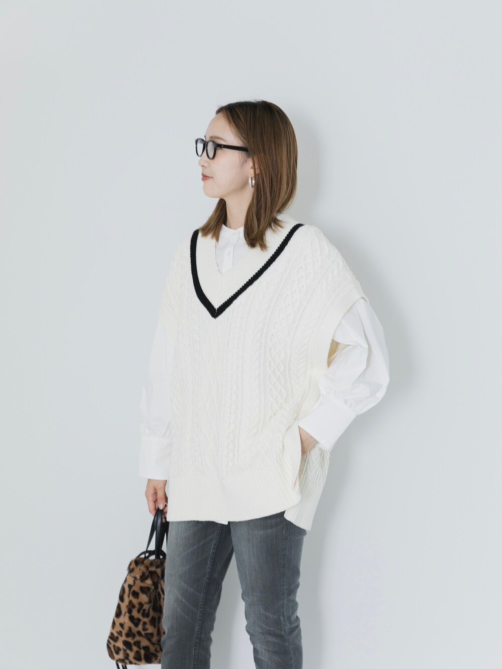 グレー系のデニムパンツ、ブラウン系のブーツ、ホワイト系のニット/セーターを着用したレディースの秋コーディネートの2枚目の写真