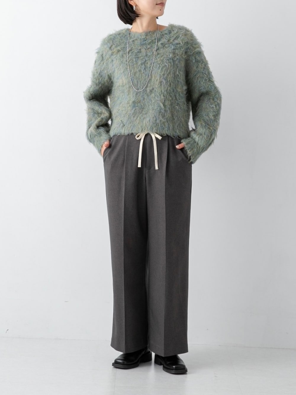 グリーン系のニット/セーター、グレー系のその他パンツを着用したレディースの冬コーディネートの2枚目の写真