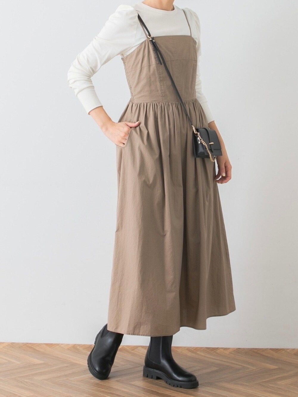 ベージュ系のワンピース、ホワイト系のTシャツ/カットソー、ブラック系のブーツを着用したレディースの秋コーディネートの4枚目の写真