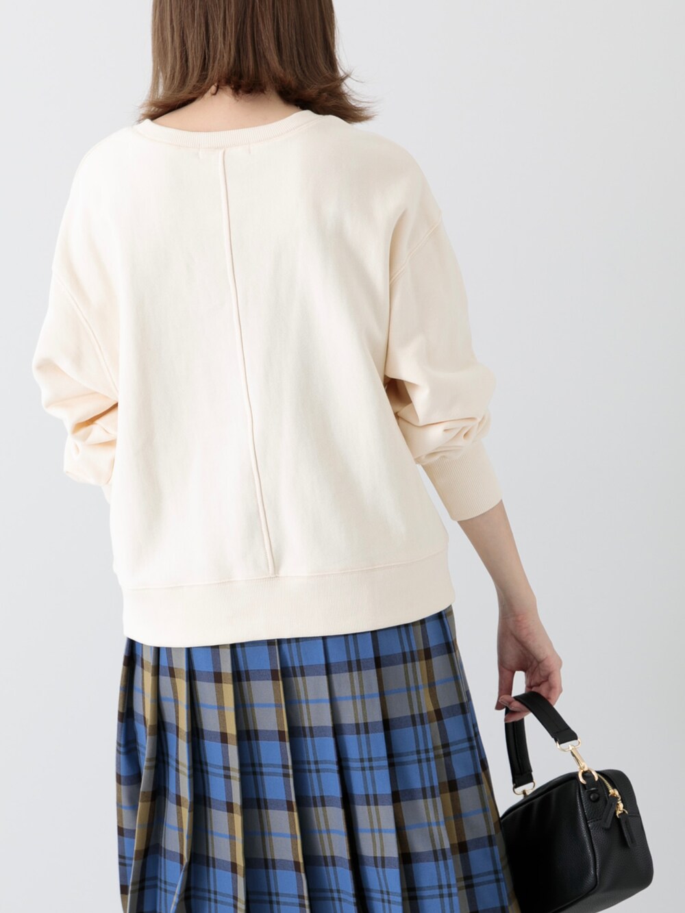 ホワイト系のスウェット、ブルー系のスカート、ブラック系のショルダーバッグを着用したレディースの冬コーディネートの2枚目の写真