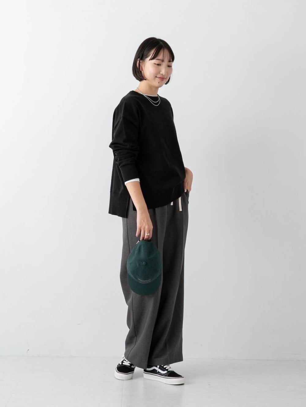 ブラック系のニット/セーター、グレー系のその他パンツ、グリーン系のキャップを着用したレディースの冬コーディネートの3枚目の写真